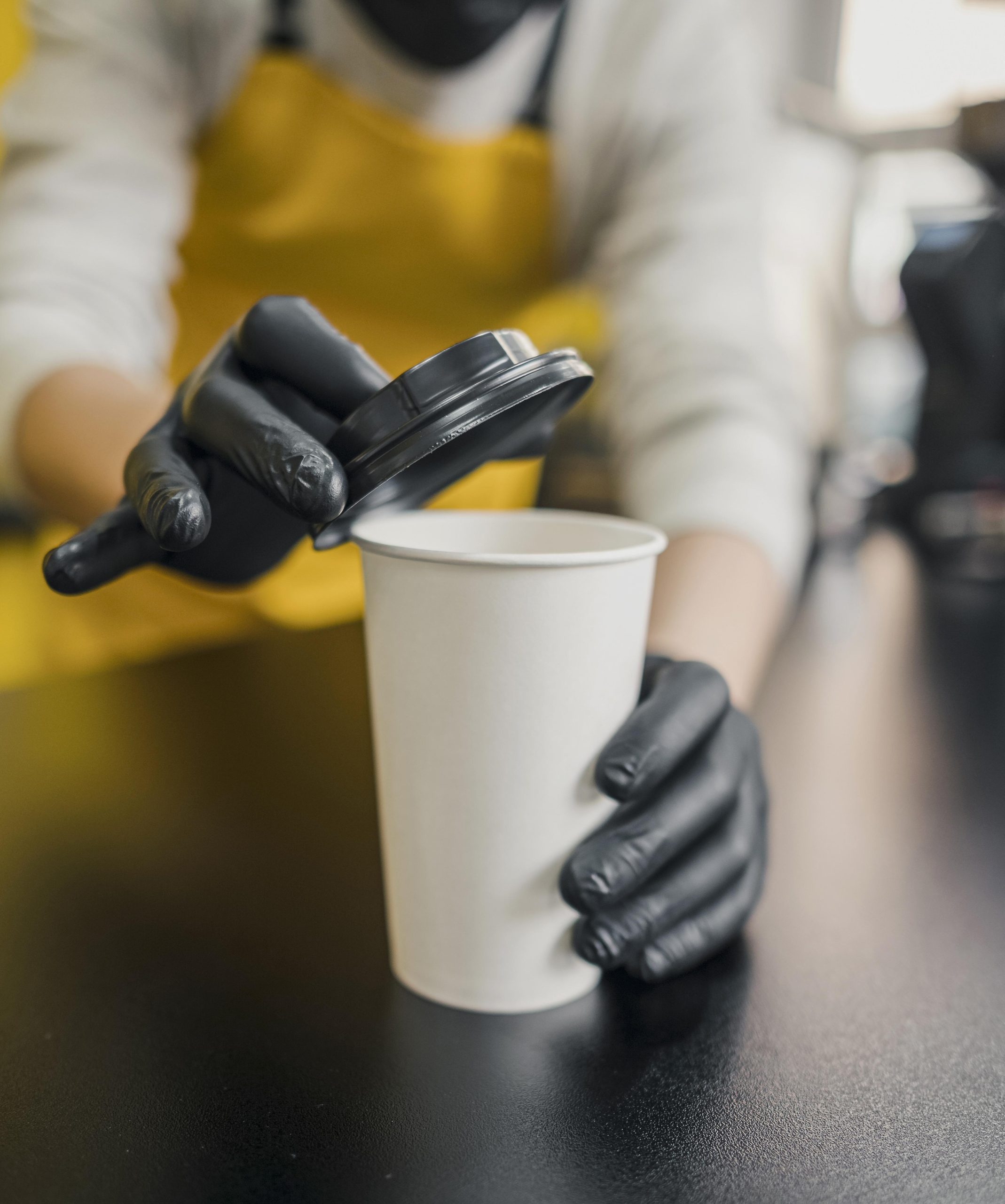 high angle barista with latex gloves putting lid coffee cup